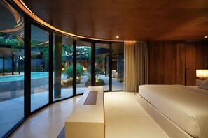 Un interior moderno con techo curvo, una cama grande y vistas a una piscina y jardín.