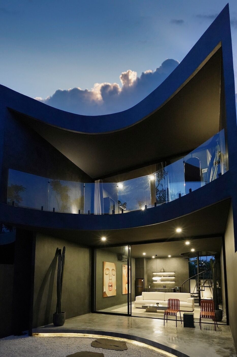 A modern building with a curved facade, large windows, and a spacious interior with a seating area.