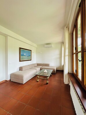 Una sala de estar con un sofá seccional color beige, una mesa de centro de vidrio y un cuadro en la pared.