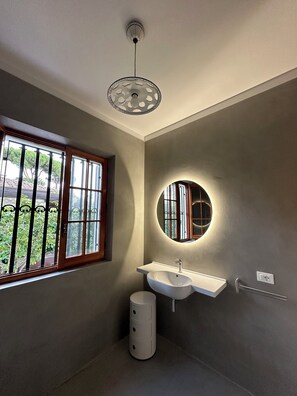 A bathroom with a window, a sink, a mirror, and a ceiling light fixture. - Sant'Elme 87 (Forte dei Marmi)
