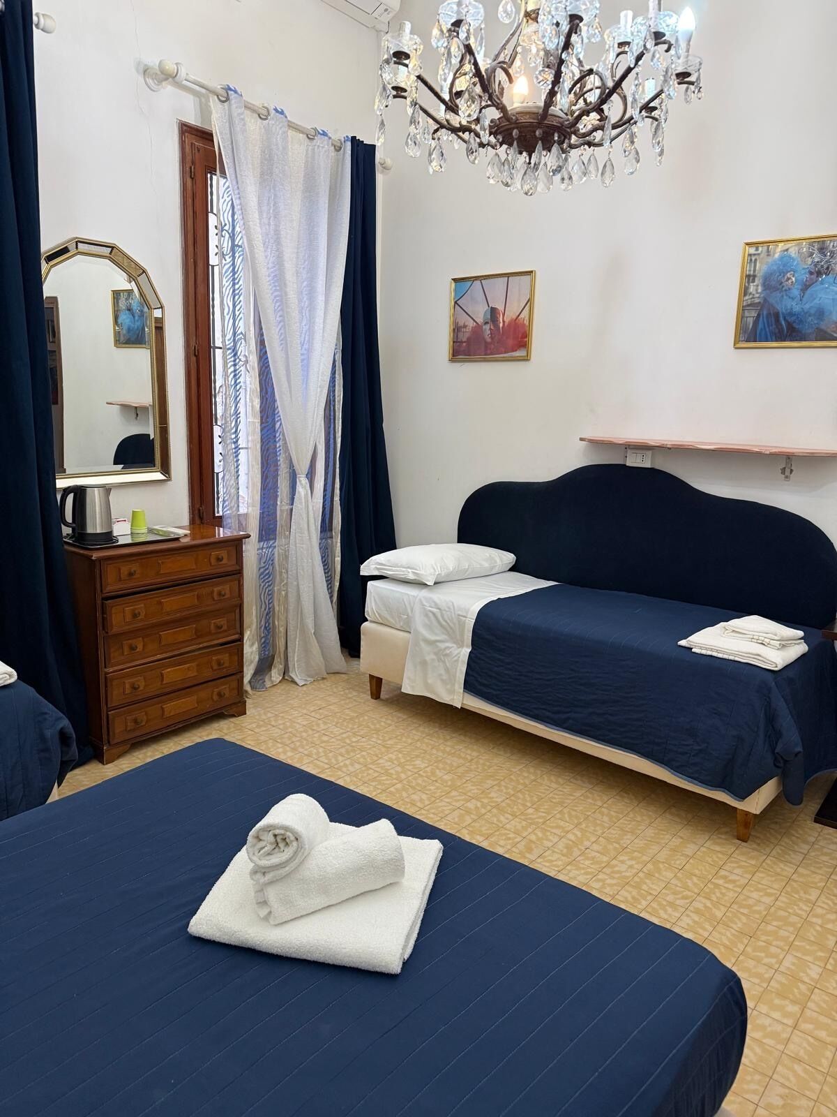 Un dormitorio con dos camas, un tocador, un espejo, una lámpara de araña y obras de arte en la pared.