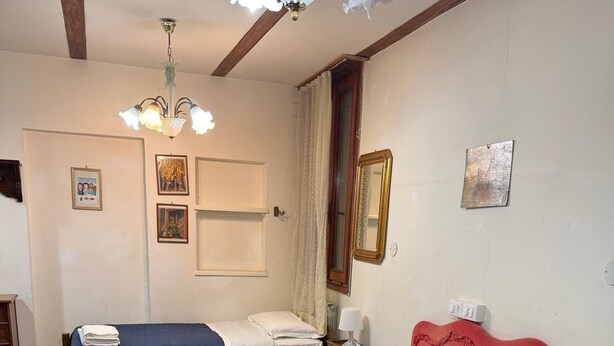 A hotel room with two beds, a chandelier, a mirror, and a window with curtains. - ALLOGGI ALLA SCALA (Venice)