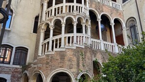 A multi-story building with a series of balconies and arches, featuring a classical architectural style. - ALLOGGI ALLA SCALA (Venice)