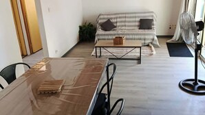 Een moderne woonkamer met een houten plafond, een bank, een salontafel en een ventilator.