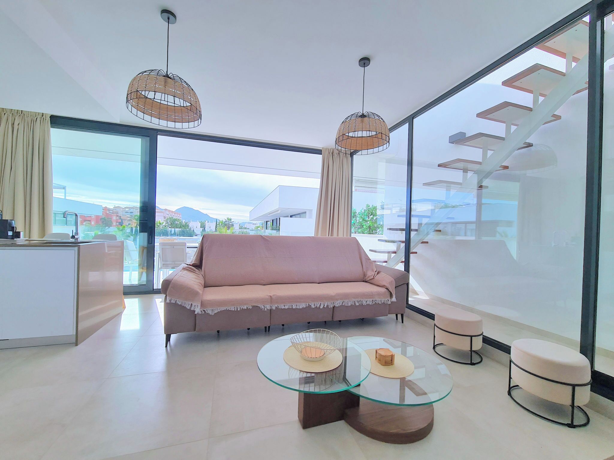 A modern living room with a sofa, a glass coffee table, and a dining area with a chair.