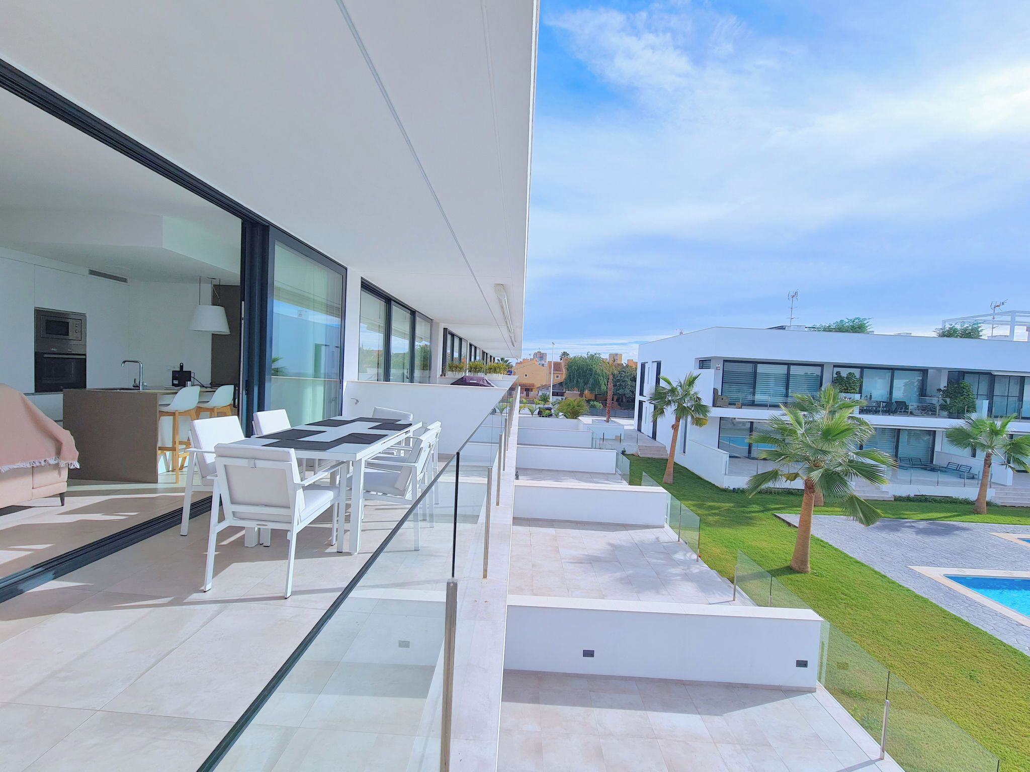 Un patio moderno al aire libre con zona de comedor, piscina y vista a edificios cercanos.