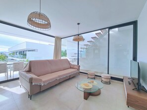 A modern living room with a sofa, a glass coffee table, and a TV stand. - Kristal by Interhome (Mar de Cristal/Playa Honda)