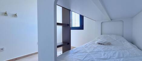 A bunk bed with a window, white walls, and a simple design.