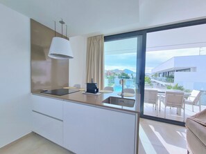 A modern kitchen with a built-in stove, a sink, and a dining area with a table and chairs. - Kristal by Interhome (Mar de Cristal/Playa Honda)