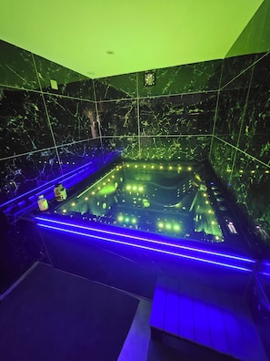 Een wellnessruimte met een bubbelbad, blauwe LED-verlichting en marmeren wanden.