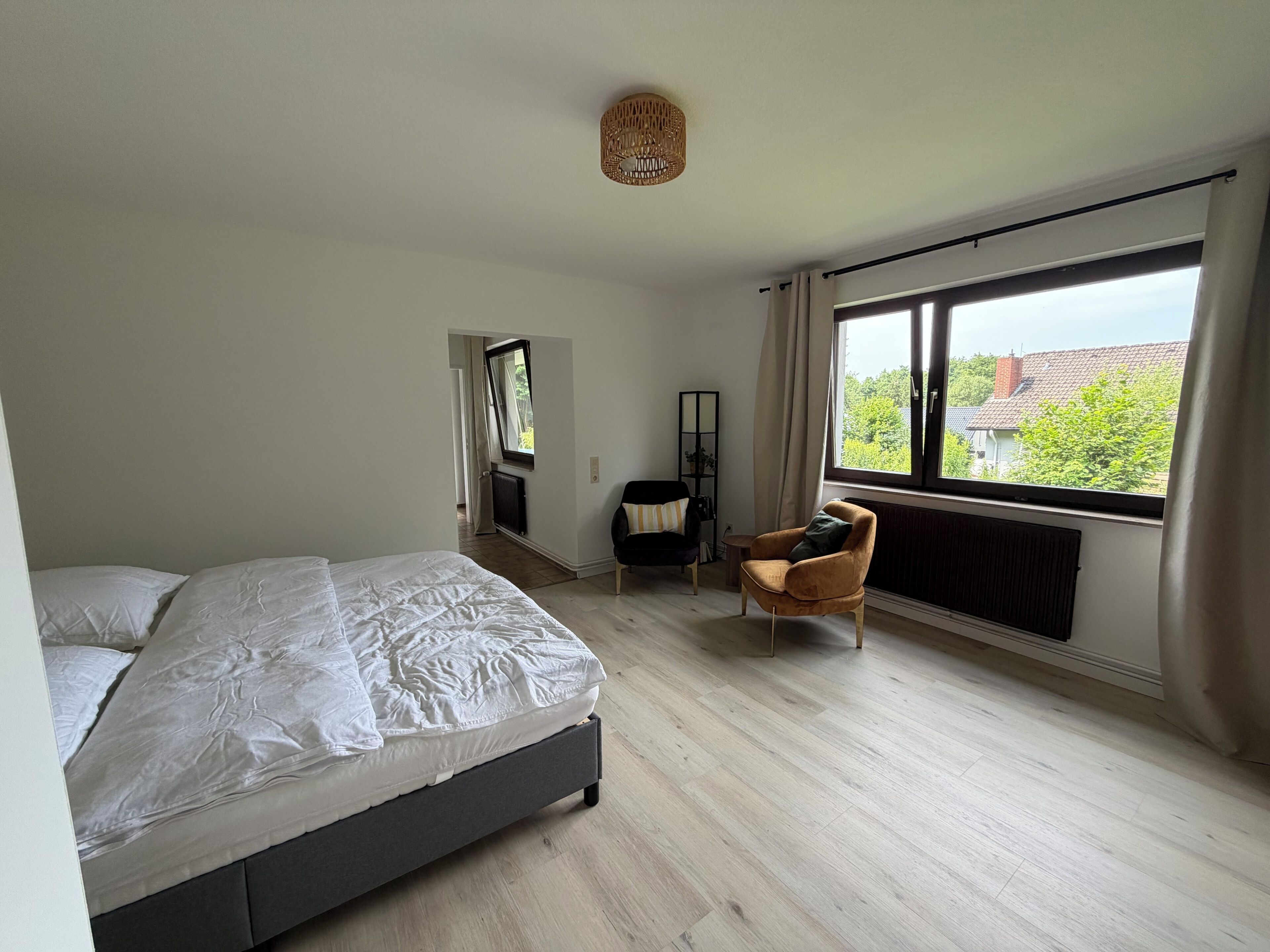 Ein Schlafzimmer mit einem Bett, einem Sessel, einem Fenster mit Aussicht und einer Heizung.