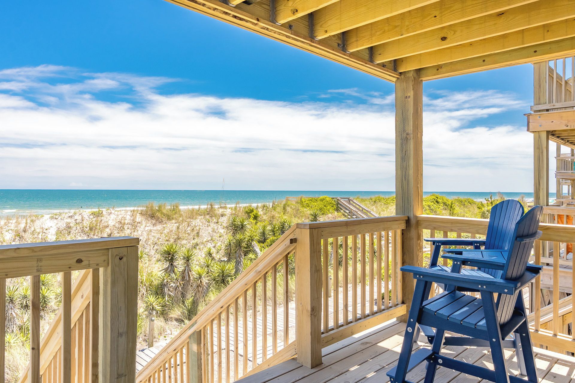 Una terraza de madera con vista a la playa y al océano.