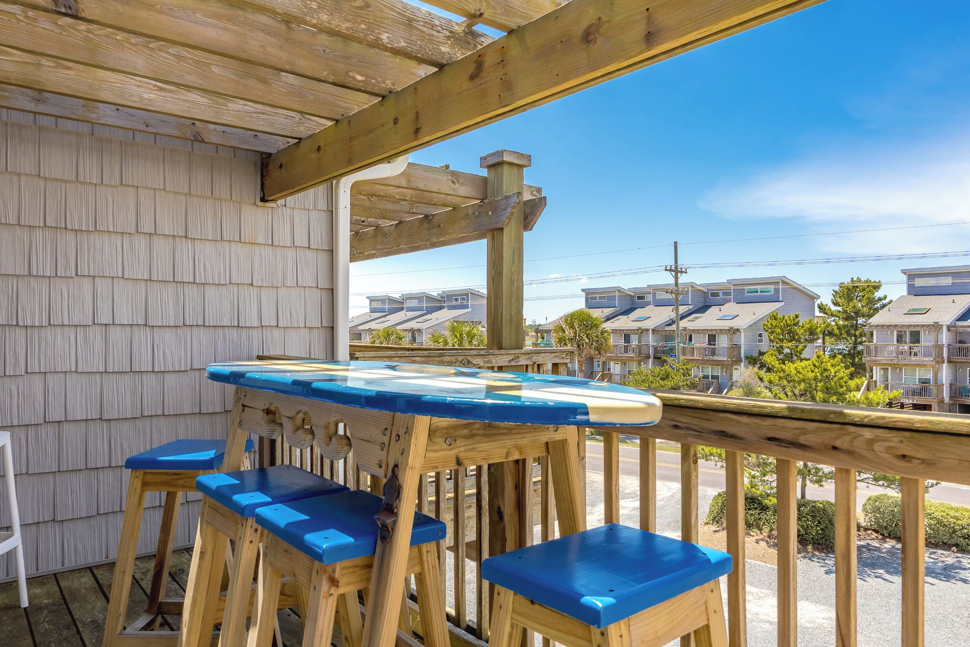 A wooden deck with a table and chairs, overlooking a residential area with houses.