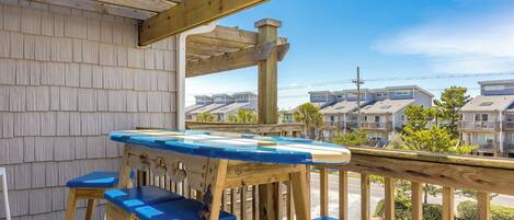 A wooden deck with a table and chairs, overlooking a residential area with houses.