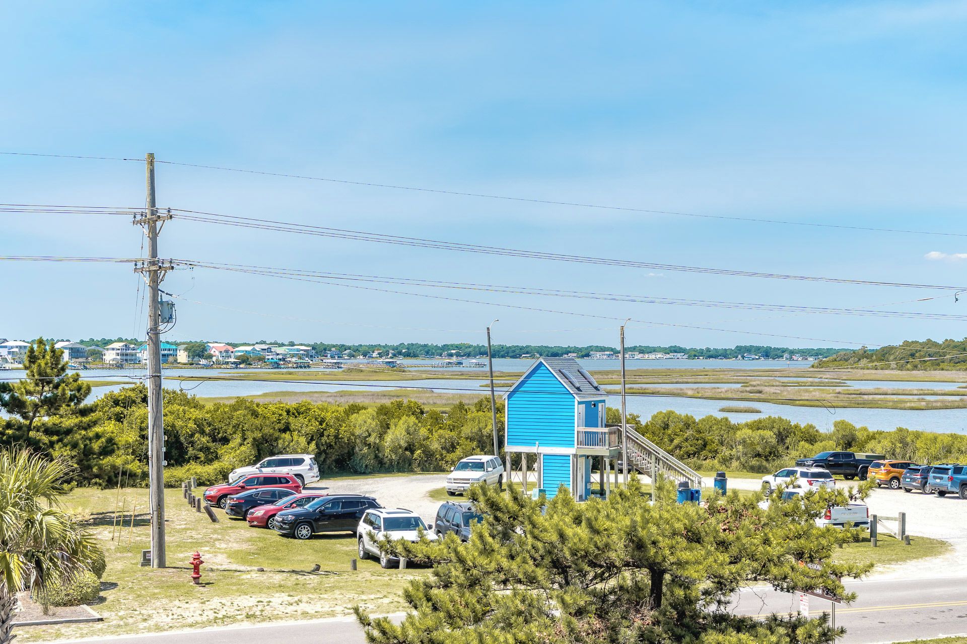 A coastal area with a blue building, parked cars, and a view of the water.