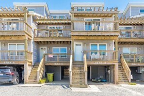 A multi-story residential building with balconies, a garage, and a visible vehicle. - Dunebeg - 3BR Oceanfront Townhome; Great Views! (North Topsail Beach)