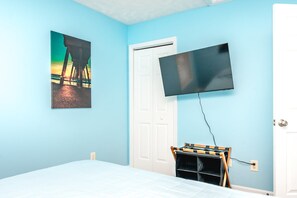 Ein Schlafzimmer mit einem Bett, einem an der Wand befestigten Fernseher und einer Tür.