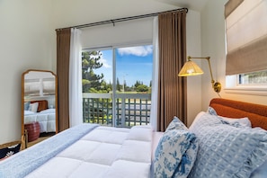 Ein Hotelzimmer mit einem großen Bett, einem fensterbelaubten Fenster, Blick ins Grüne und einer Lampe.
