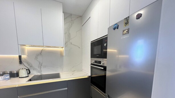 A modern kitchen with a built-in oven, a refrigerator, and a microwave. - Sea View Retreat - Beachfront Two-Bedroom Penthouse (Calpe)