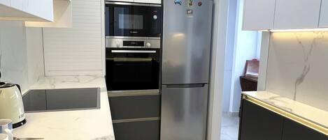Una cocina moderna con horno empotrado, refrigerador de acero inoxidable y encimera de mármol.