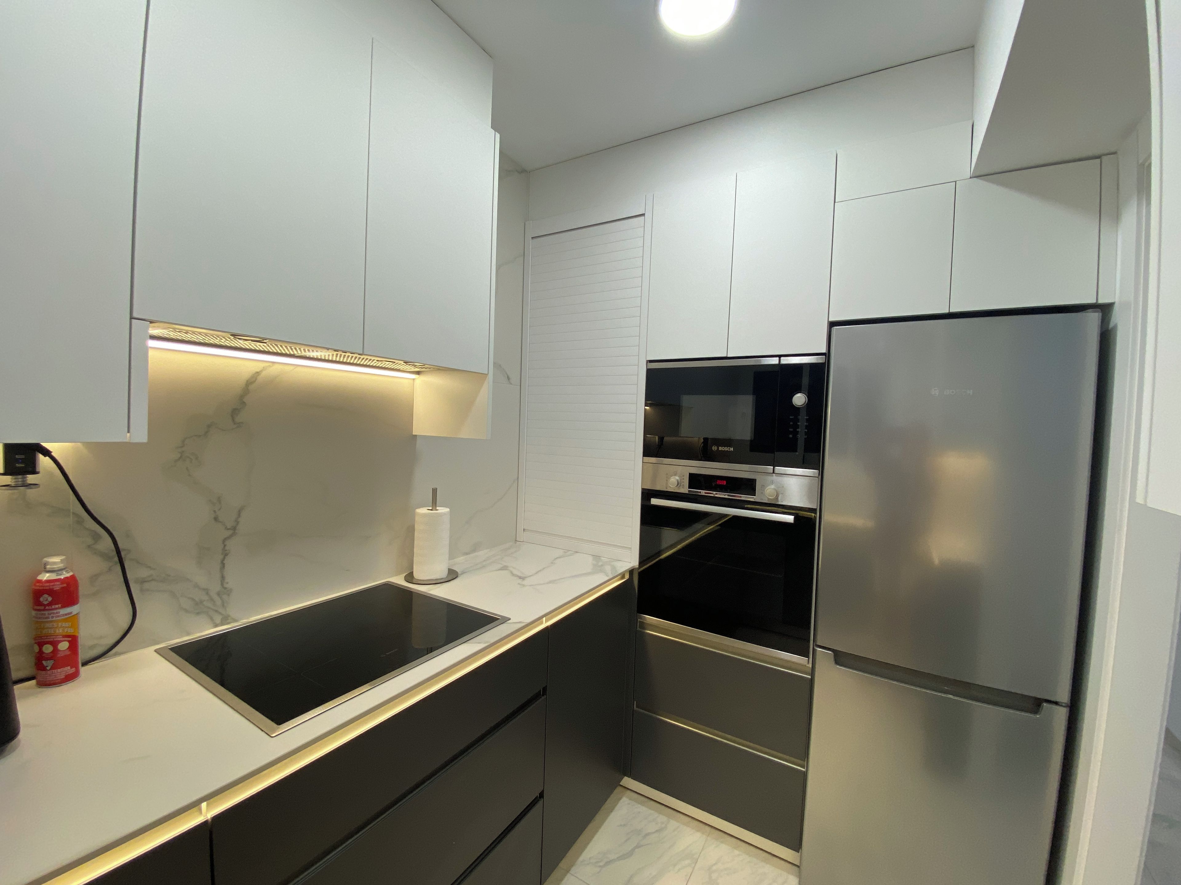 Una cocina moderna con horno empotrado, microondas y refrigerador de acero inoxidable.