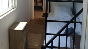 A bunk bed room with a window, a wooden chest, and a door leading to another room. - Victor's House at the Foot of Sainte Victoire (Vauvenargues)