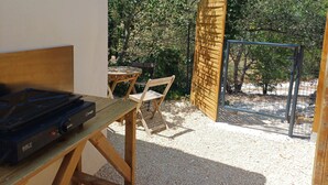 Un espace patio aménagé avec une table et des chaises, un barbecue et une clôture en bois.