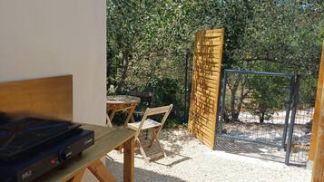 A patio area with a table and chairs, a grill, and a wooden fence.
