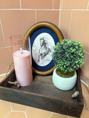 A wooden tray with a candle, a framed horse drawing, and a potted plant.