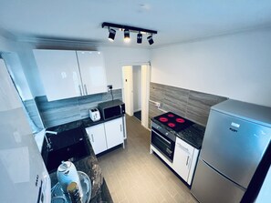 Et moderne køkken med indbygget ovn, et køleskab og en brødrister på bordpladen.