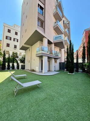 A modern apartment building with a flat roof, balconies, and a well-maintained lawn. - Apartment with a private garden and a private parking space (Roma)