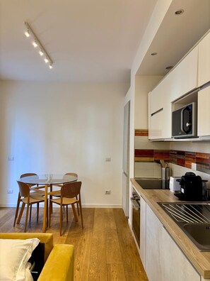 A modern kitchen with a microwave, toaster, and coffee maker. There is a dining area with a table and chairs. - Apartment with a private garden and a private parking space (Roma)