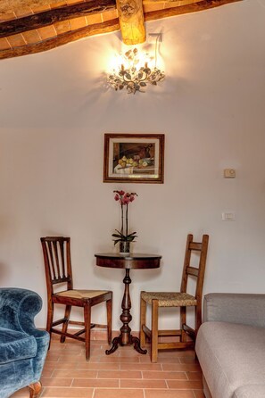Una habitación con una mesa de madera, dos sillas, un cuadro y una araña.