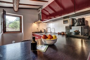 Una cocina moderna con encimera de madera, un cuenco de fruta, un hervidor y una cafetera.