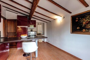 Una cocina con techo de madera, encimera blanca, un lavabo y una silla.