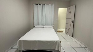 Un dormitorio con una cama individual, una puerta y una alfombra pequeña.
