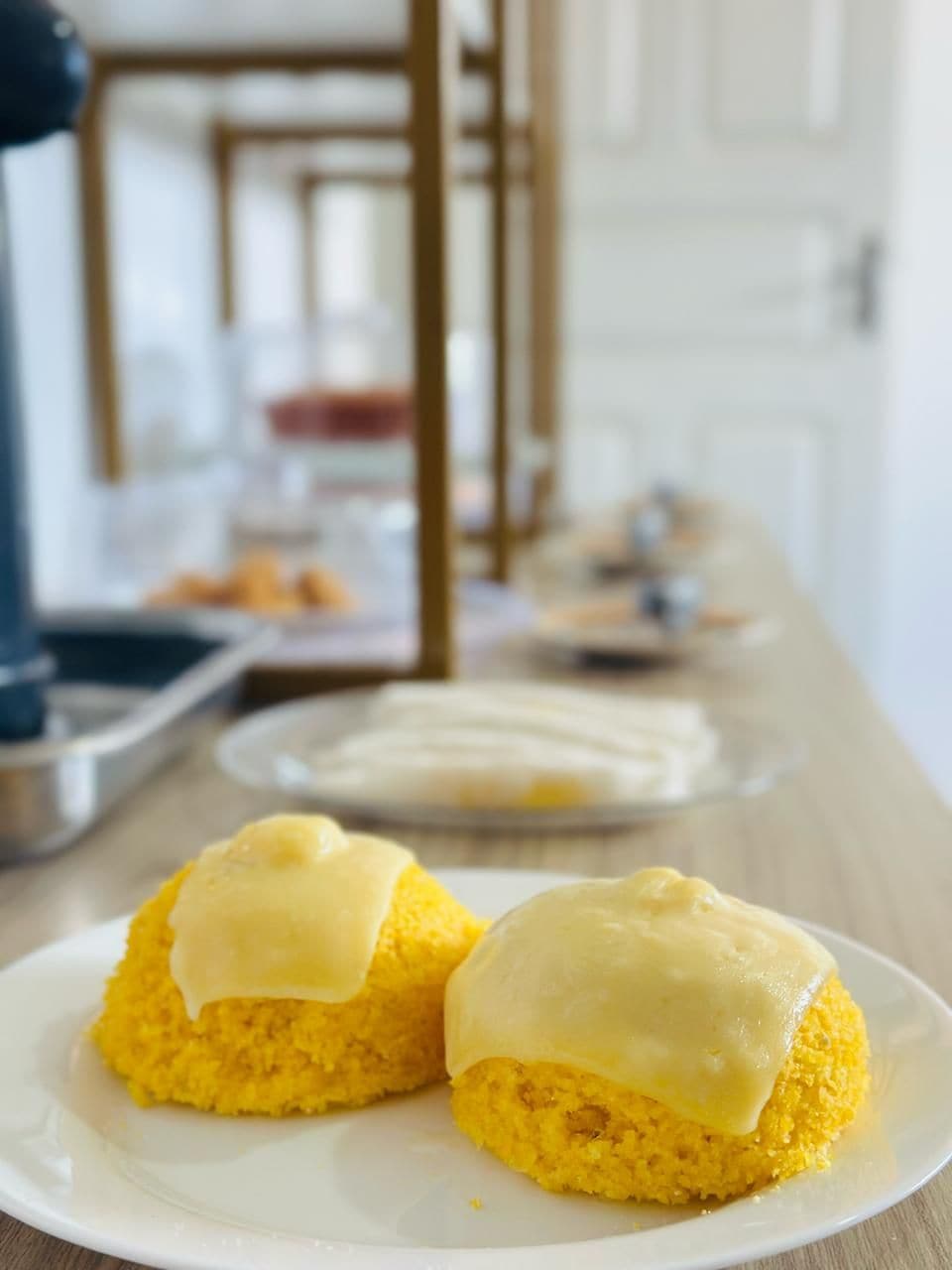 Dos muffins de pan de maíz amarillo con cobertura blanca sobre un plato blanco.