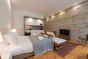 A modern bedroom with a bed, bedside tables, a TV, and a kitchenette. - Rico's Apartment 1B - Prime Location in Central Porto (Porto)