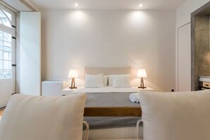 Habitación de hotel con cama, dos lámparas de noche, ventana y vistas al exterior.