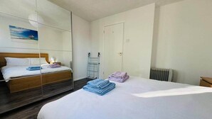Habitación de hotel con cama, espejo, radiador y puerta.