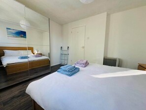 Una habitació d'hotel amb un llit, un mirall, un radiador i una porta.
