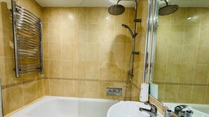 Un baño con bañera, lavamanos y zona de ducha.