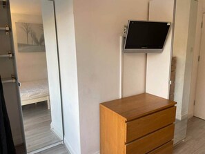 Ein Schlafzimmer mit einem Bett, einem Holzschrank und einem an der Wand befestigten Fernseher.