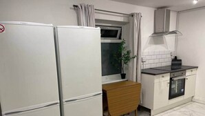Een praktische keuken met een koelkast, oven en een eettafeltje.