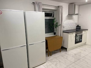 Eine kleine Küche mit Kühlschrank, Backofen und einem Esstisch.