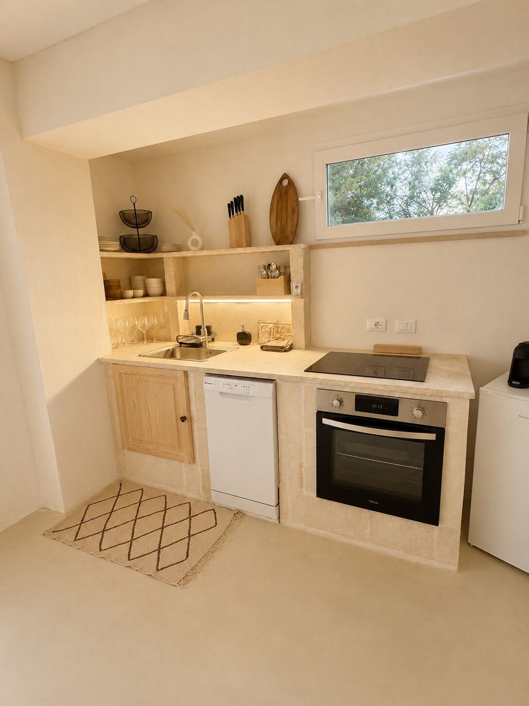 Eine kompakte Küche mit Geschirrspüler, Backofen und einem Fenster über der Spüle.
