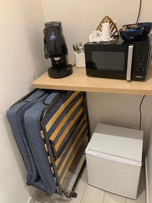 Una kitchenette equipada con cafetera, microondas y recipientes de almacenamiento.