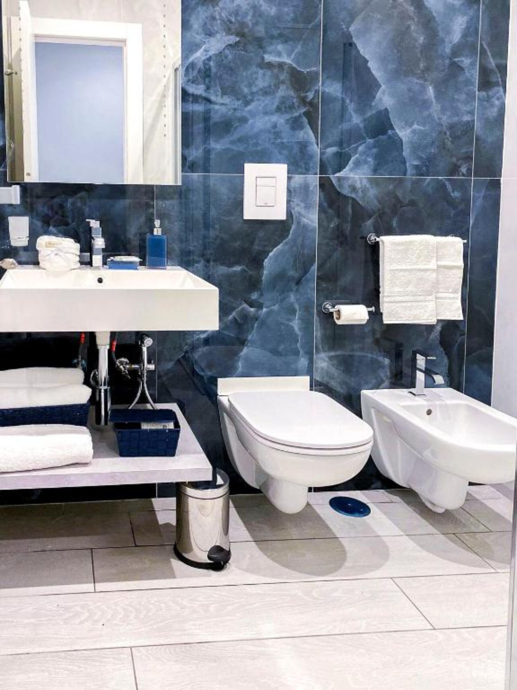 Un bagno moderno con lavandino bianco, un water, un bidet e una vasca bidet.