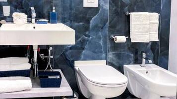 Un bagno moderno con lavandino bianco, un water, un bidet e una vasca bidet.