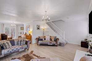 A spacious living room with a high ceiling, a staircase, and a dining area. - Glenmore Lodge | Luxury Braemar Highland Retreat | Walk to Village | Sleeps 6 (Braemar)